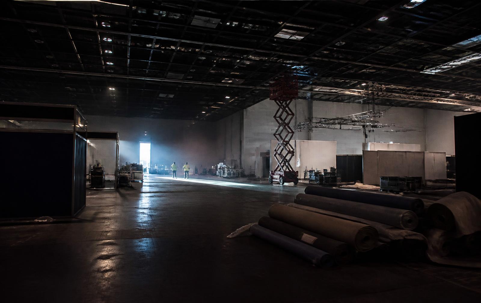Exhibition hall during strike-out with half-dismantled booths and carpet rolls